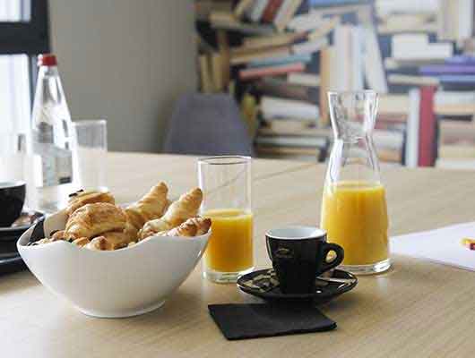 Table avec tasses de café, jus d'orange et croissants